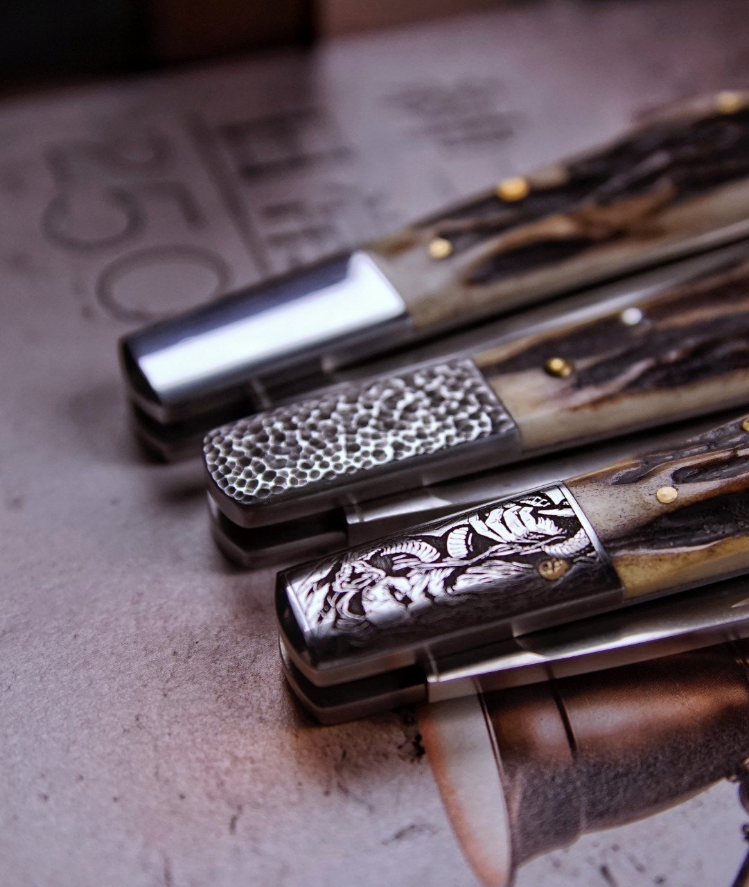 Engraved bolster detail on three 32°N slipjoint knives with sambar stag handles